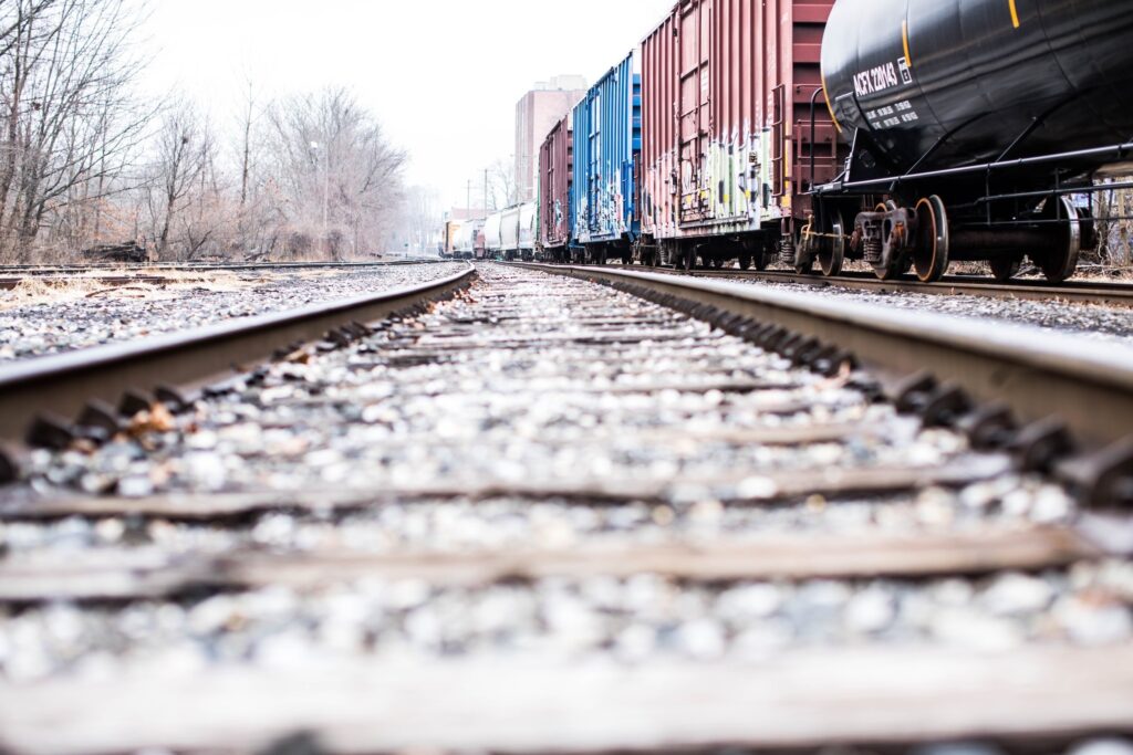 A view of railroad tracks with freight train cars lined along the tracks, captured from a low angle.
