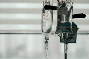 Two intravenous (IV) bags hanging on a pole, with a blurred background and soft lighting.