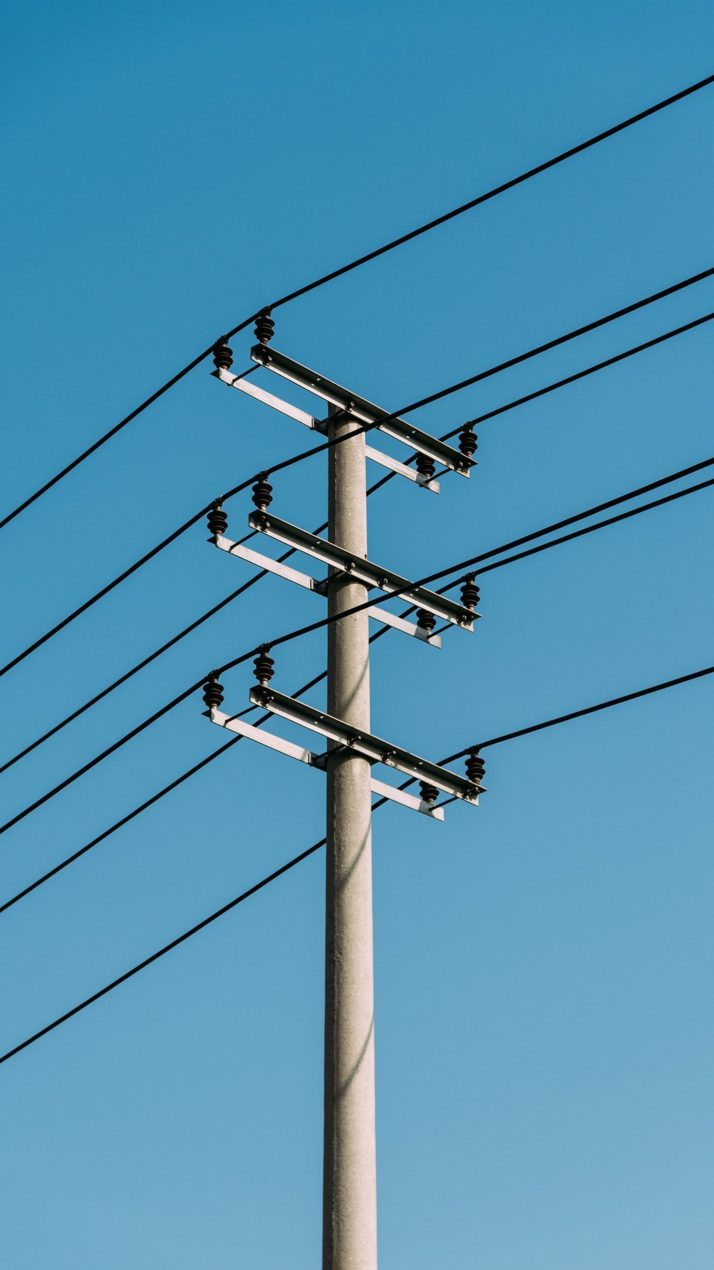 A utility pole with power lines against a clear blue sky.