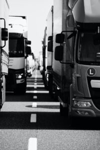 A close-up view of several trucks parked side by side on a road, captured in black and white.